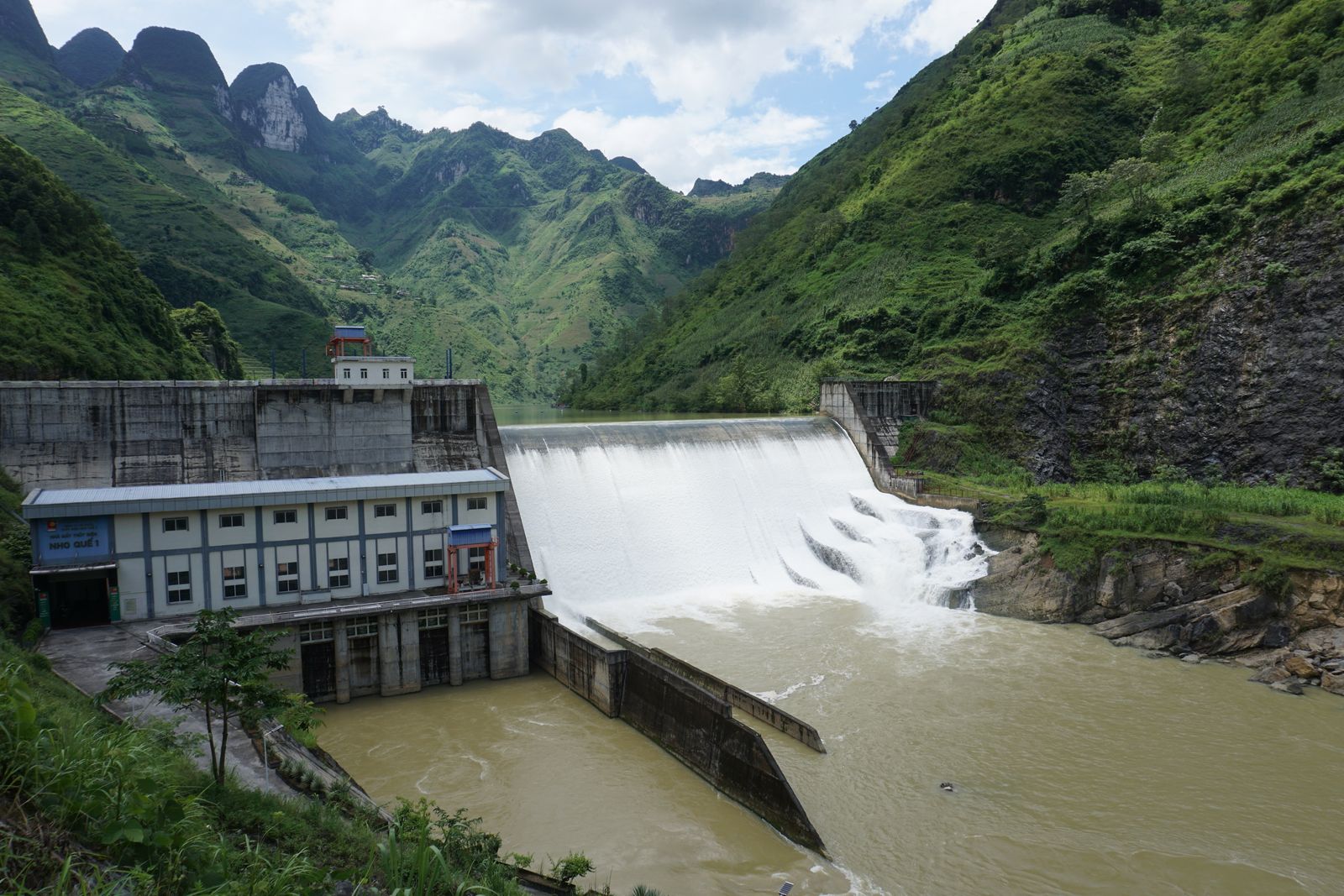 Hydroelectric dam and reservoir in a forested Southeast Asian valley, representing renewable energy and carbon credit infrastructure